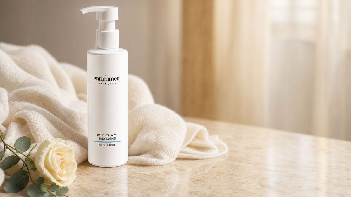 Enrichment Skincare Delicate Baby Body Lotion on marble beside a soft knitted blanket and a cream rose