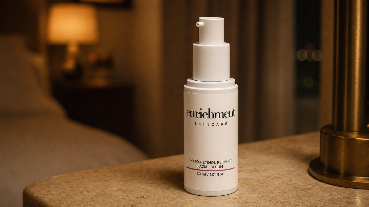Enrichment Skincare Phyto-Retinol Refining Facial Serum on a stone bedside table in warm evening lamplight