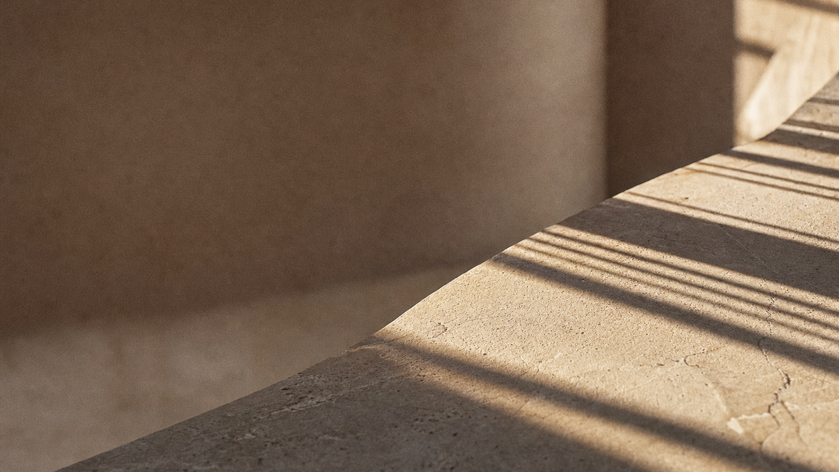 Hard-edged sunlight and shadow raking across a honed stone slab, evoking the sun's changing angle through the day