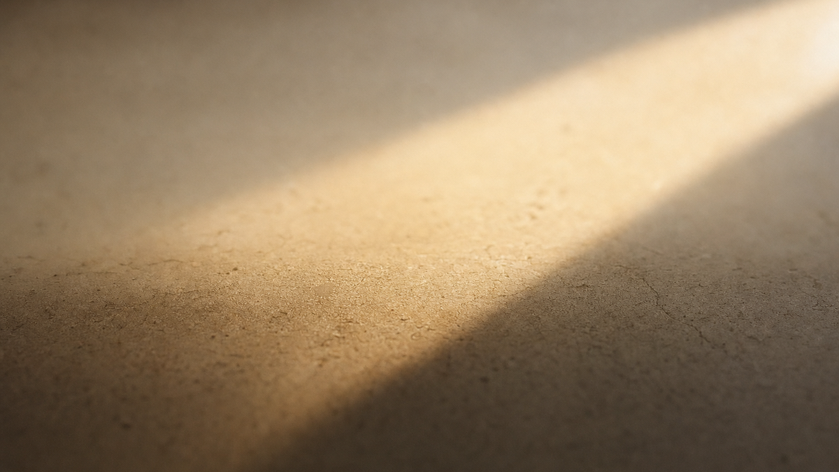 A diagonal band of warm sunlight falling across a pale stone surface