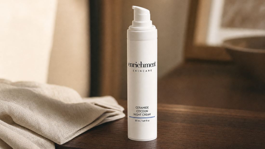 Enrichment Skincare Ceramide Cocoon Night Cream pump bottle on a wooden bedside table beside a folded linen cloth