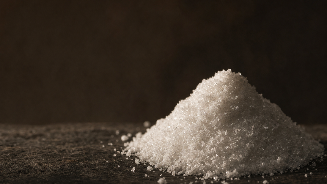 A sculpted mound of fine white crystalline powder catching dramatic light on a dark stone surface