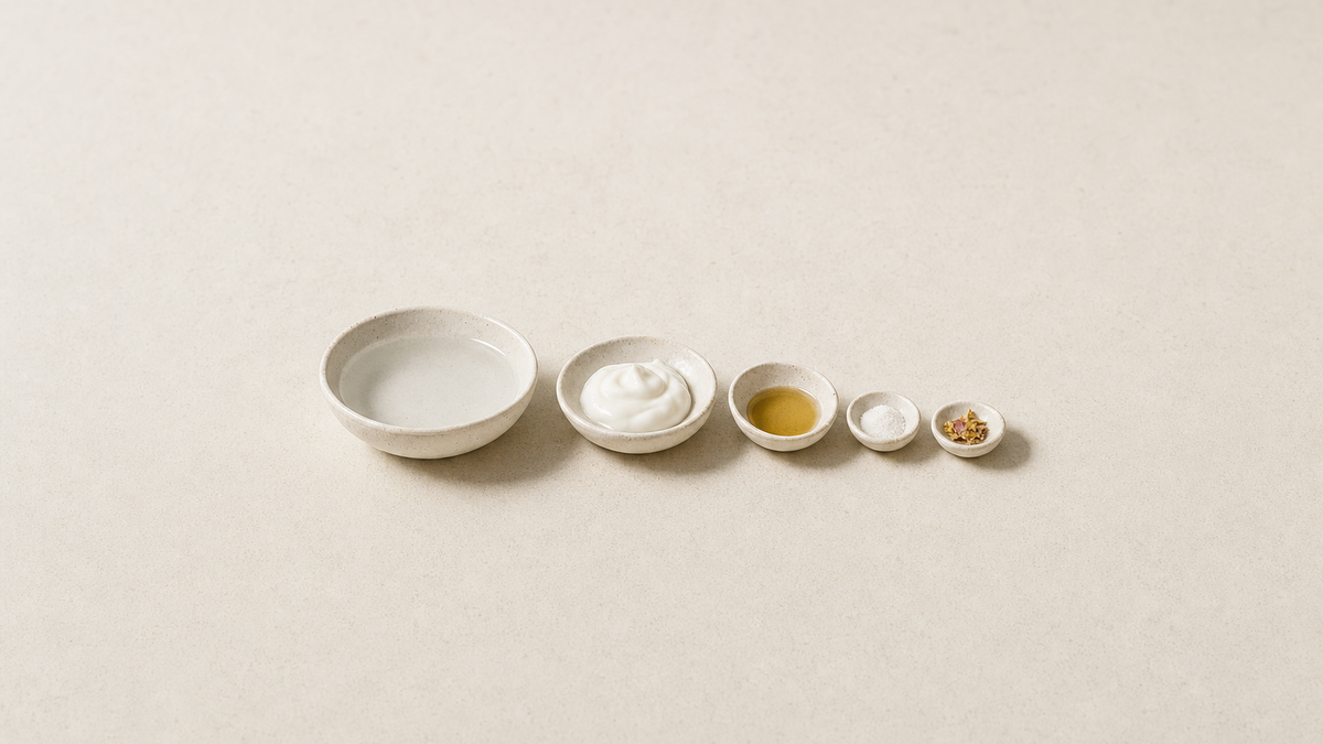Five small ceramic bowls in decreasing size holding water, cream, golden oil, white powder and dried petals