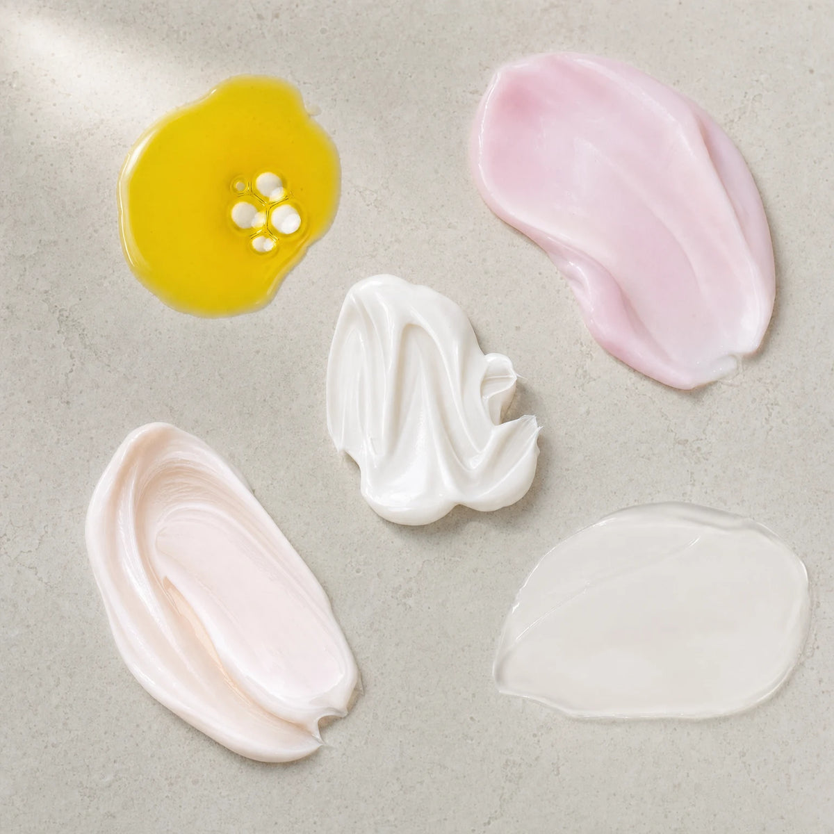 Swatches of the five formulas: golden oil, pink serum, white cream, peach lotion and clear cleansing milk