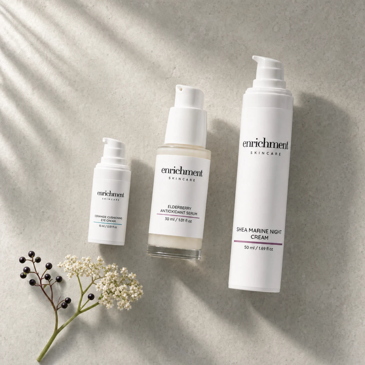The three products in the set laid out in usage order with a sprig of elderflower