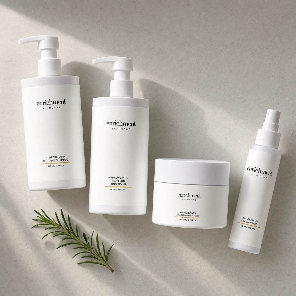 The four Hydrokeratin products laid out from top left to bottom right in usage order, with a small sprig of rosemary