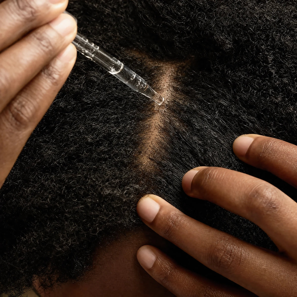 Dropper applying Lactic Acid Clear Scalp Serum directly to the parted scalp