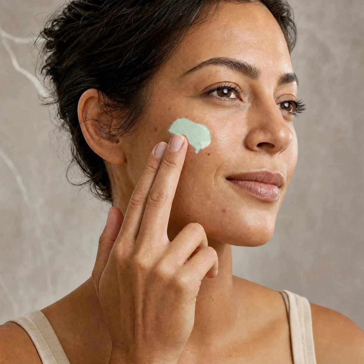 Woman applying Maté Leaf Clarifying Moisturiser to her cheek