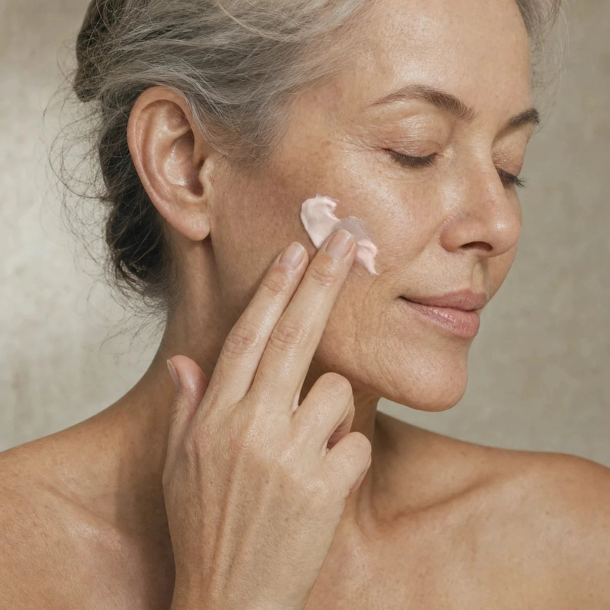 Older woman applying Hexapeptide Smoothing Face Cream to her cheek