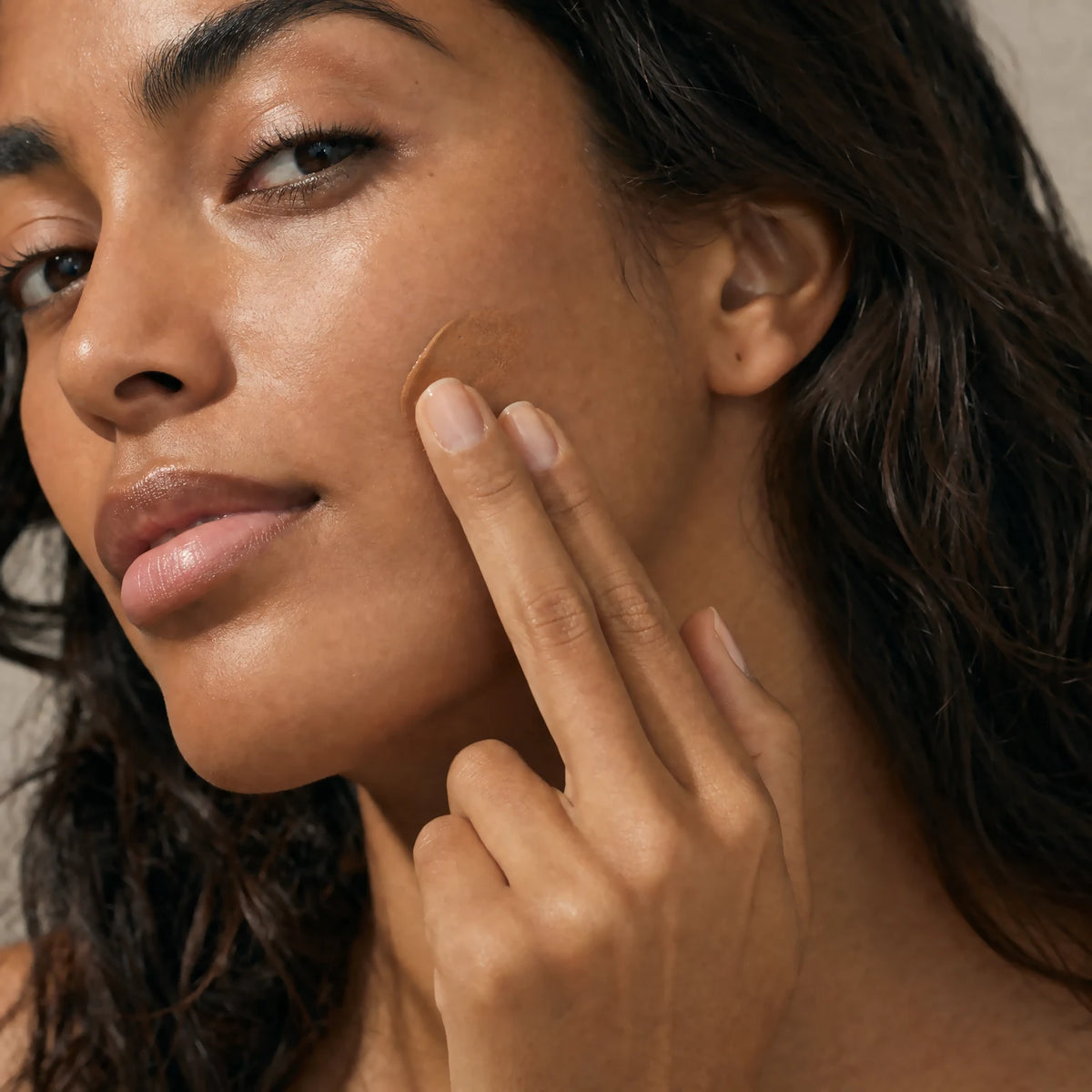Two fingertips applying the Ceramide CC Stick SPF30 Tan tint into matching skin