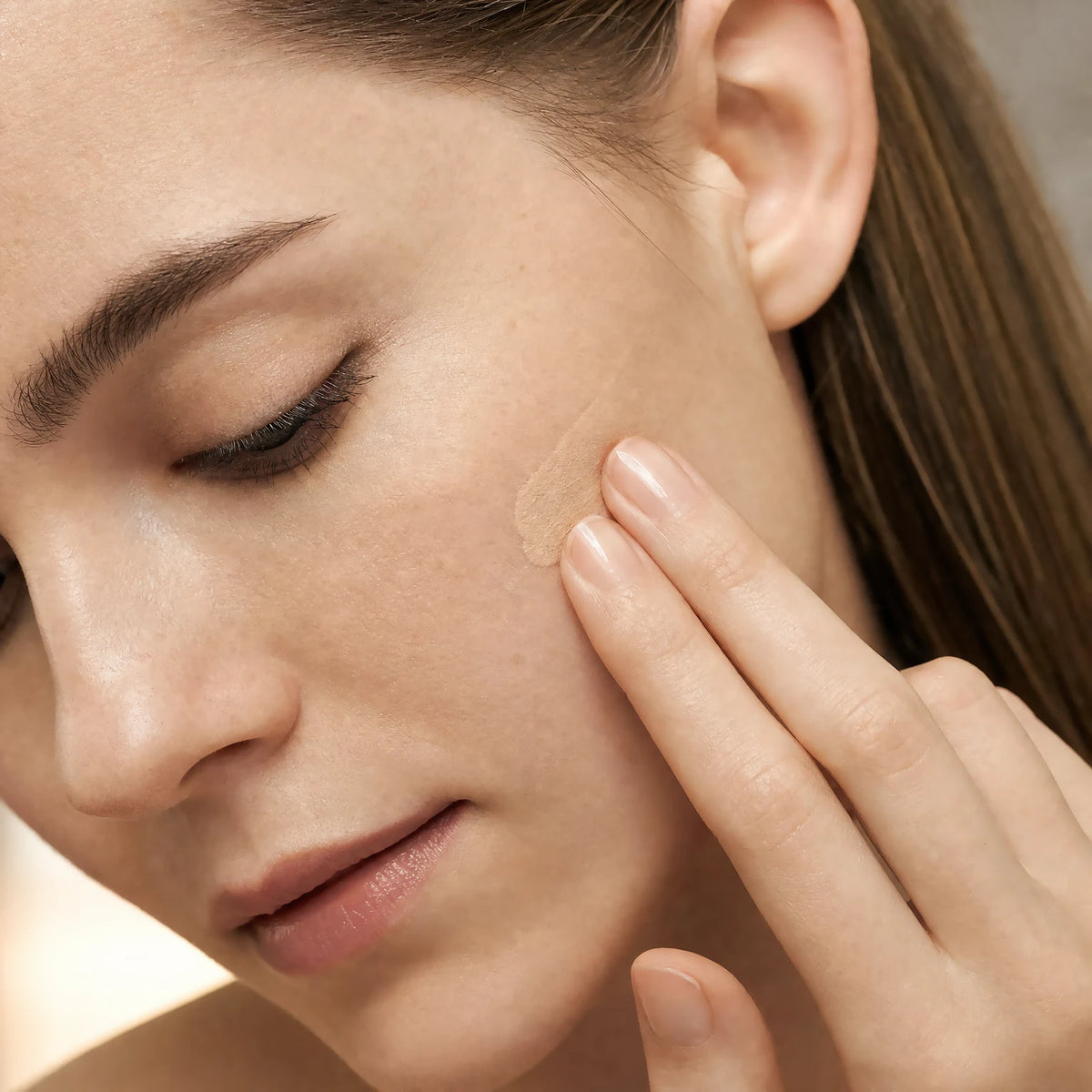 Two fingertips applying the Ceramide CC Stick SPF30 Light tint into matching skin
