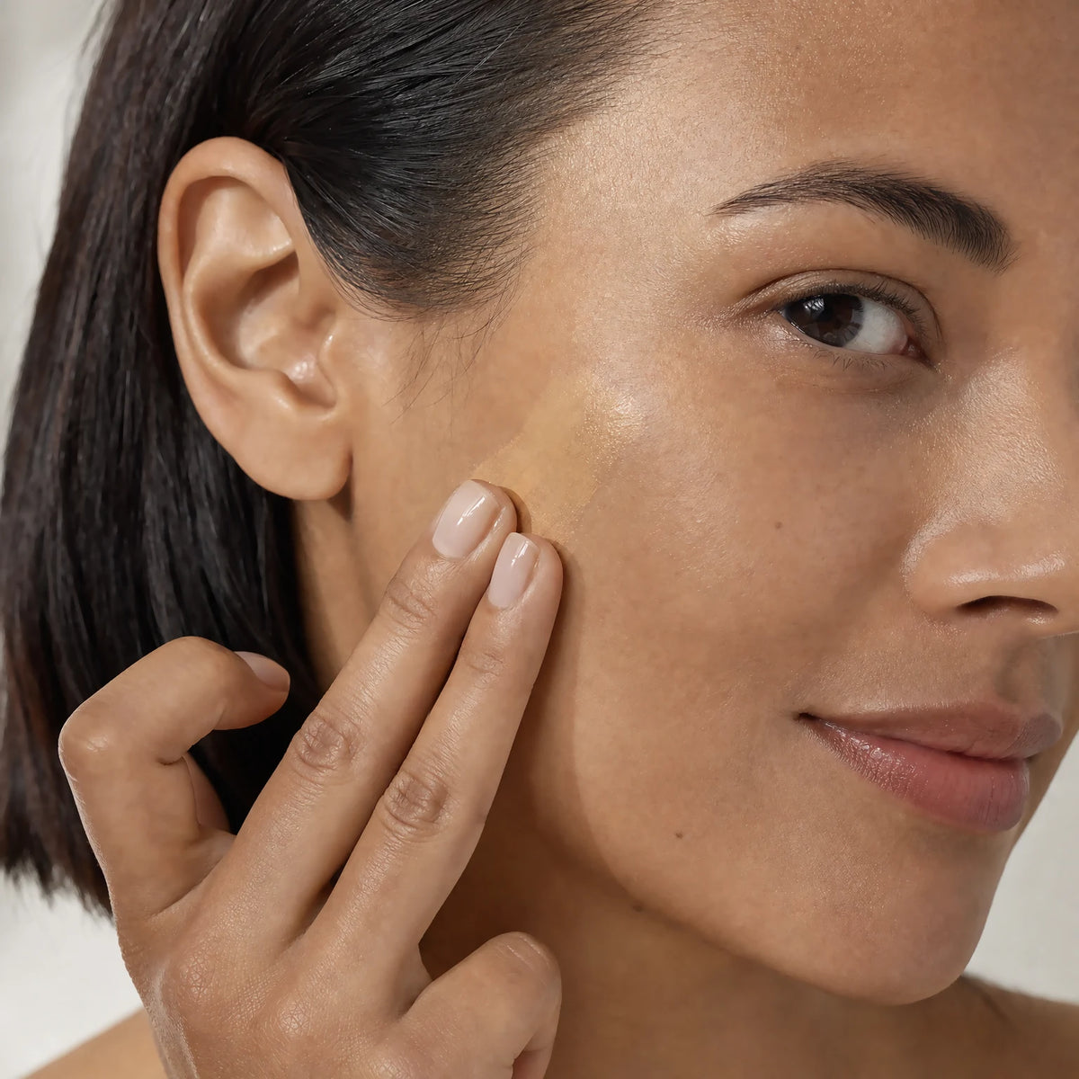 Two fingertips applying the Ceramide CC Stick SPF30 Medium tint into matching skin