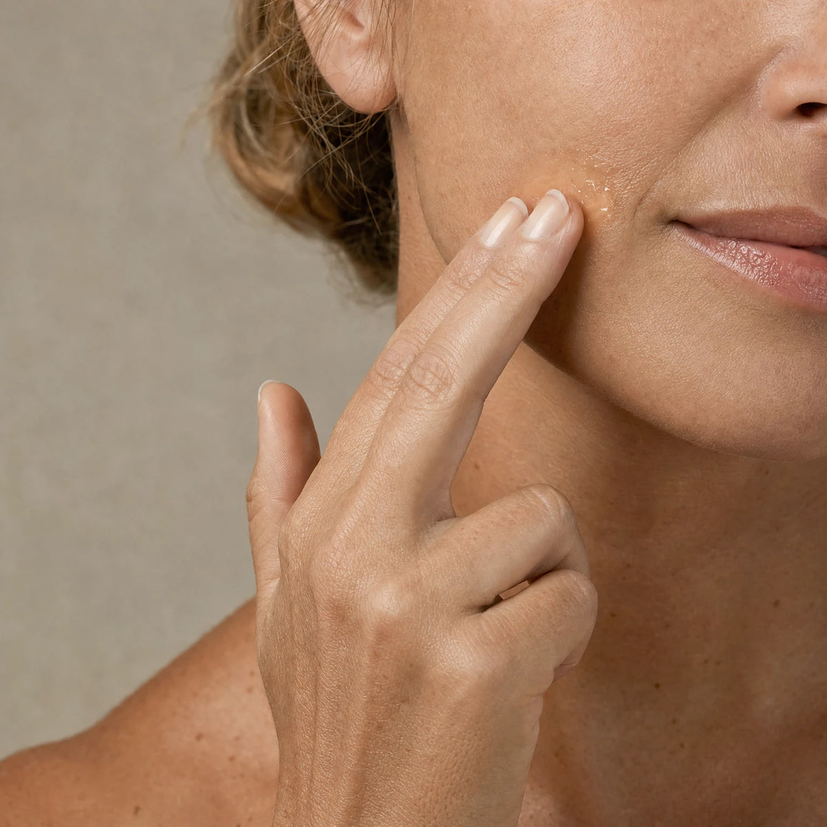 Middle-aged woman applying Hexapeptide Smoothing Serum to her cheek