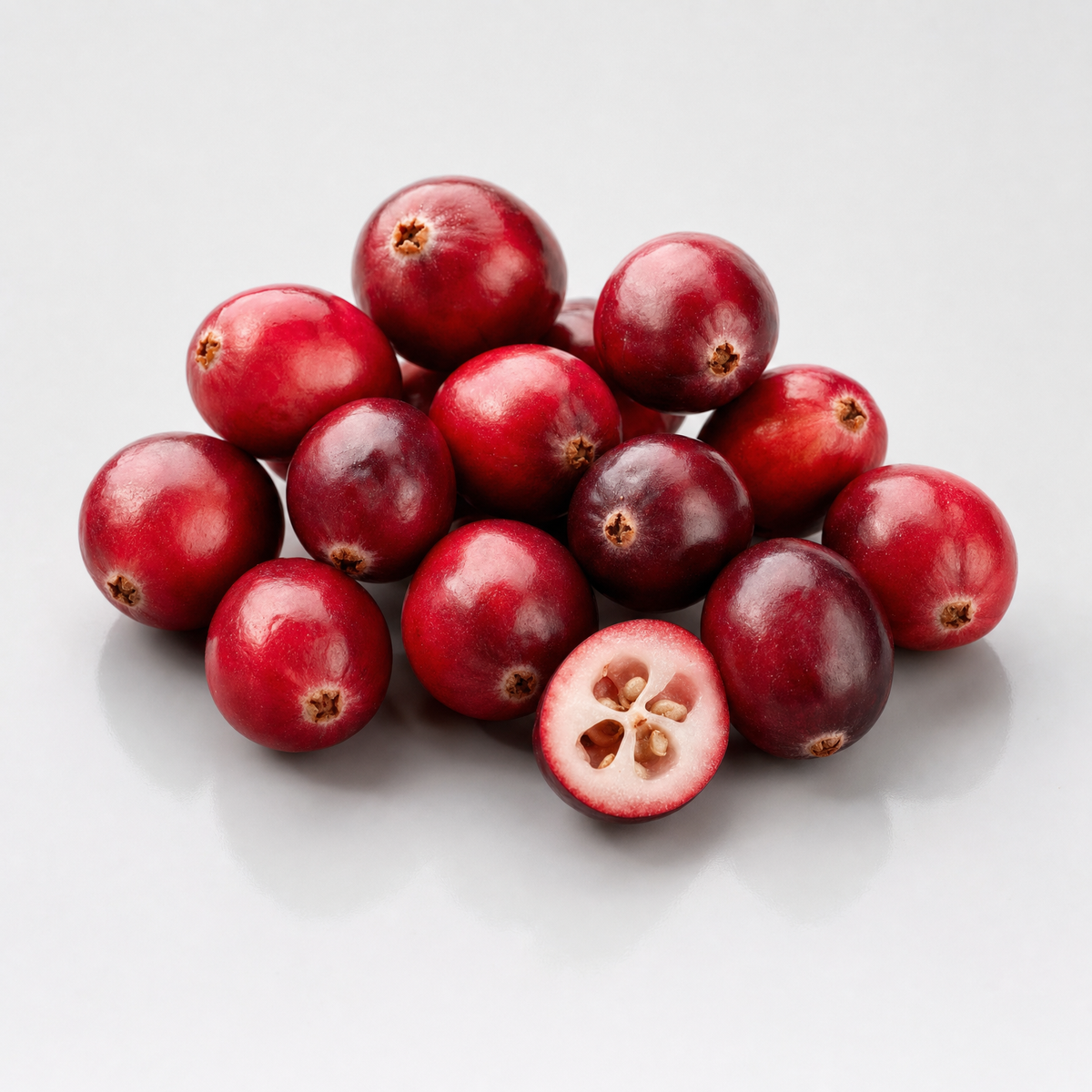 A cluster of fresh cranberries with one berry cut in half