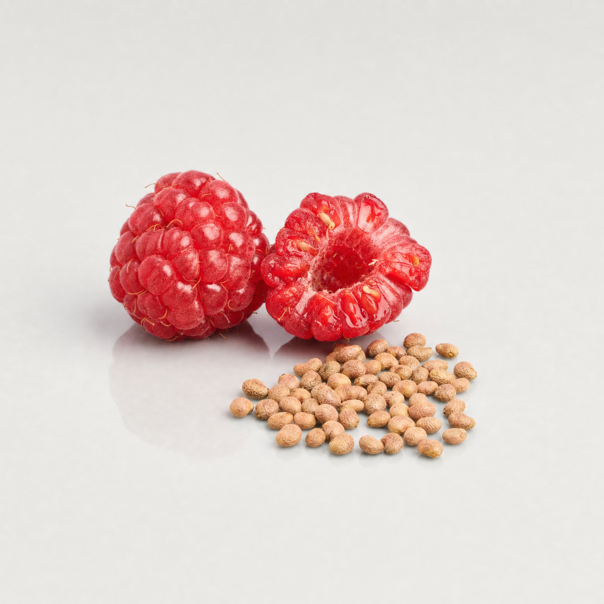 Fresh raspberries beside a small heap of tan raspberry seeds