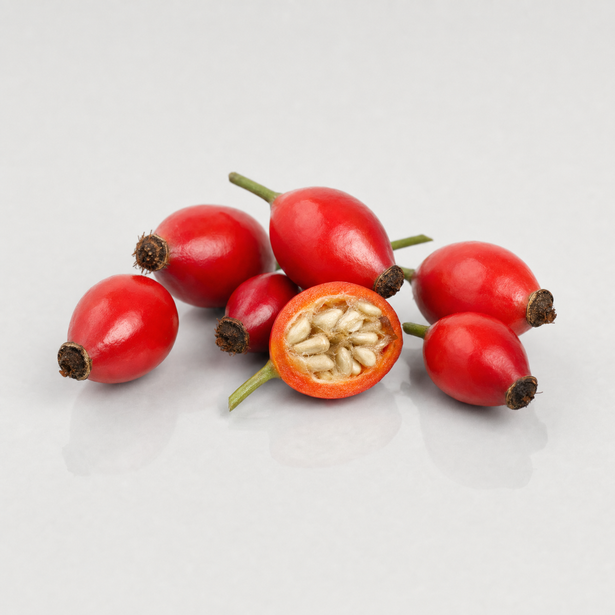 Fresh glossy red dog rose hips, one cut in half to show the seeds