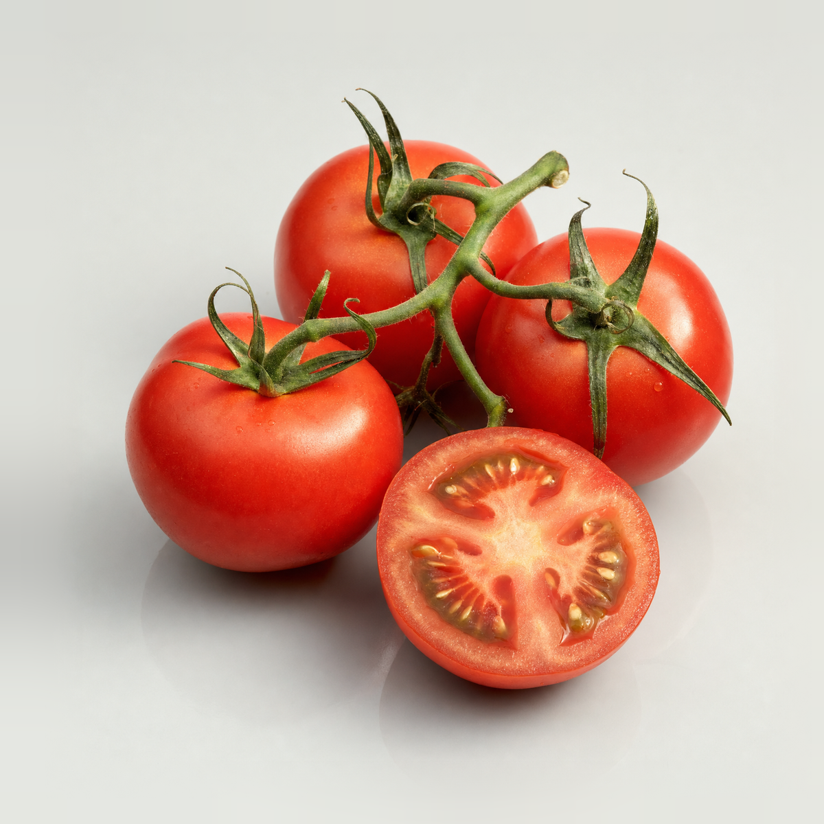 Ripe tomatoes on the vine beside a tomato cut in half