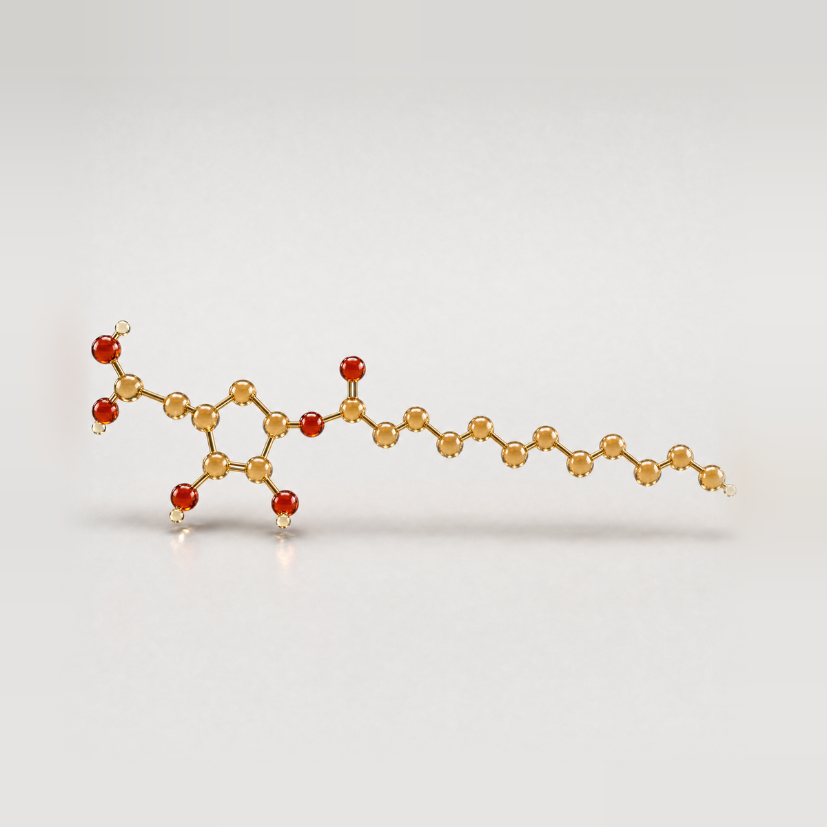 A gold glass ball-and-stick model of the ascorbyl palmitate molecule: a vitamin C ring joined to a long fatty-acid tail