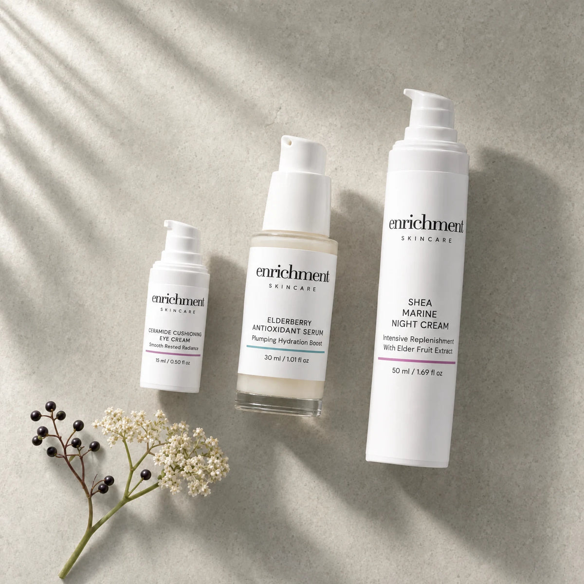 The three products in the set laid out in usage order with a sprig of elderflower