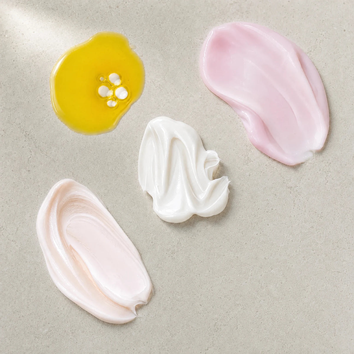Swatches of the four formulas: golden oil, pink serum, white cream and peach lotion